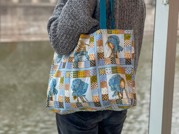 A person faces away holding a tote bag over their shoulder.